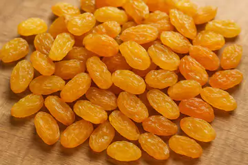 golden raisins spreaded on a wooden table.