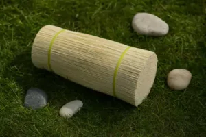 stack of bamboo incense sticks gently placed on grass along with a few round rocks.