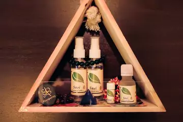 savi essential oil spray placed on a triangle wooden shelf.