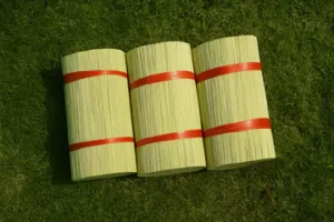 top angle shot of three stacks of bamboo sticks on grass.