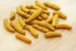 whole turmeric sticks spreaded out on a wooden table.